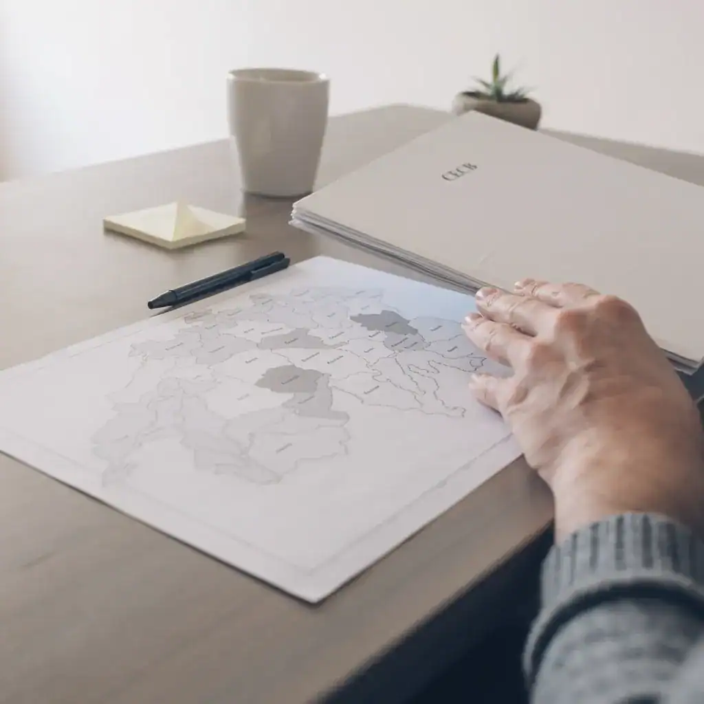Carte géographique en noir et blanc sur bureau avec stylo, carnet et tasse.